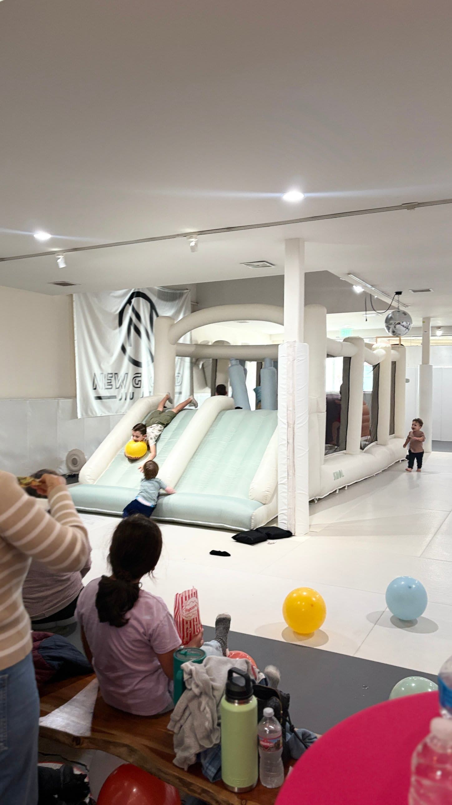 Kids racing down the double slide of the indoor bounce house during a birthday party