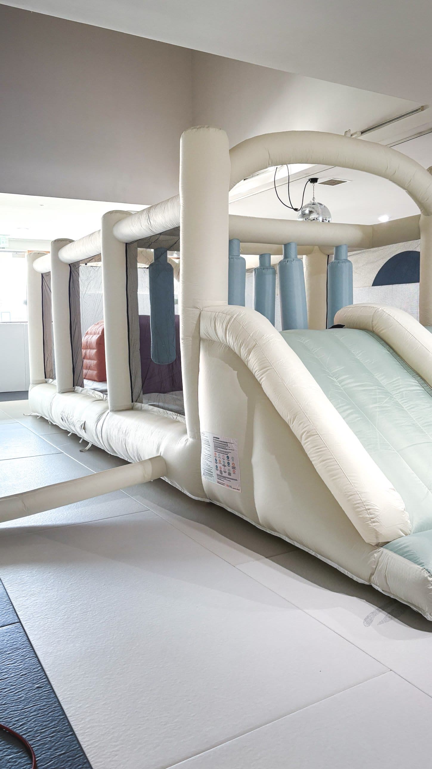 Indoor bounce house with obstacle course and double slide set up on the academy mats